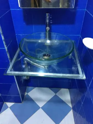 a glass sink in a blue tiled bathroom at larc in Deroua
