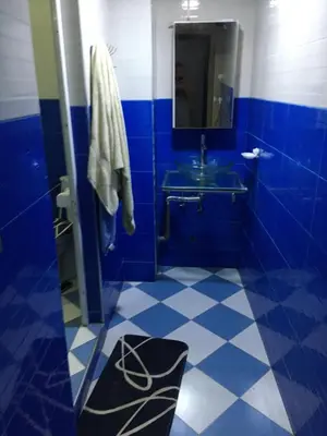 a blue tiled bathroom with a sink and a mirror at larc in Deroua