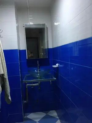 a blue bathroom with a sink and a mirror at larc in Deroua