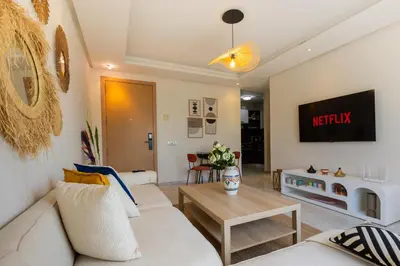 a living room with a white couch and a tv at Prestigia Luxe Suite by MERAT HOME in Rabat