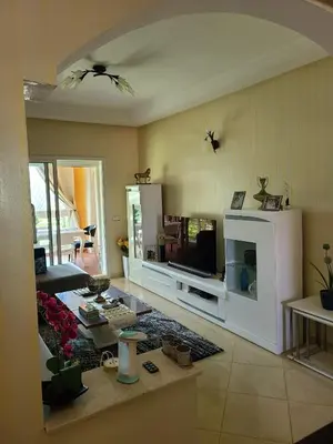 a living room with a couch and a tv in it at Ricoflores palm benslimane in O Ben Slimane