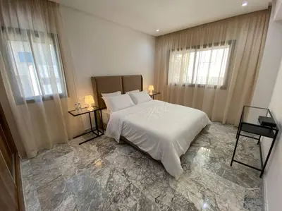 a bedroom with a large white bed and two windows at Appartement neuf luxe OLM à Rabat in Rabat