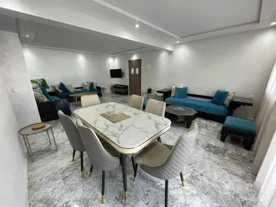 a living room with a table and chairs and a couch at Appartement neuf luxe OLM à Rabat in Rabat