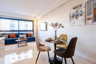 a living room with a table and chairs at Emplacement Chic Lumineux & Central Près du Consulat Américain 2 minutes de Twin Center Gauthier Casablanca in Casablanca