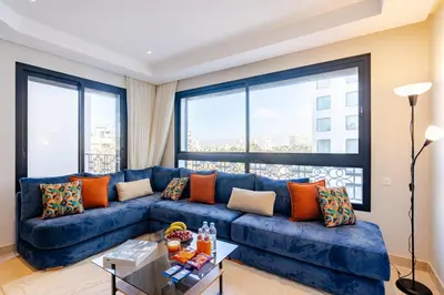 a blue couch in a living room with large windows at Emplacement Chic Lumineux & Central Près du Consulat Américain 2 minutes de Twin Center Gauthier Casablanca in Casablanca