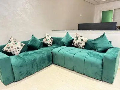 a green couch with pillows in a living room at Nice appartement In Rabat-Temara in Temara