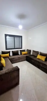 a living room with a large couch with yellow pillows at Bel Appartement neuf à 7 min de la plage avec piscine privée in Mohammedia