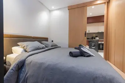 a bedroom with a large bed and a kitchen at So Chic & Lumineux Appartement Avec Terrasse Ensoleillée Au Coeur De Maarif Quartier Palmier Avec Parking Prés de Tramway Et Restaurants Luigi Casablanca in Casablanca