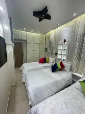 a bedroom with three beds and a ceiling fan at Spacieux appartement corniche in Casablanca