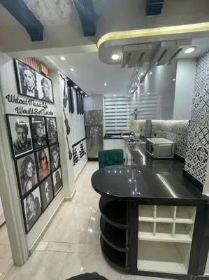 a room with a kitchen with a table and pictures on the wall at Spacieux appartement corniche in Casablanca
