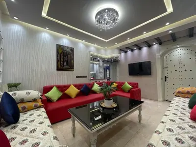 a living room with a red couch and a tv at Spacieux appartement corniche in Casablanca