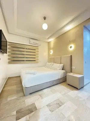 a bedroom with a large bed and a television at SUITOUISS - Agdal 3 - Appartement à 2 minutes de la gare de train TGV Rabat in Rabat