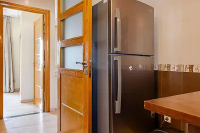a kitchen with a refrigerator and a wooden door at Appartement avec terrasse en plein centre de ville in Casablanca