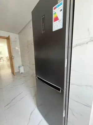 a stainless steel refrigerator in a kitchen with marble floors at Appartement Les pieds dans l'eau in Oulad Kerroum