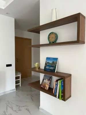 a room with wooden shelves and a clock on a wall at Appartement Les pieds dans l'eau in Oulad Kerroum