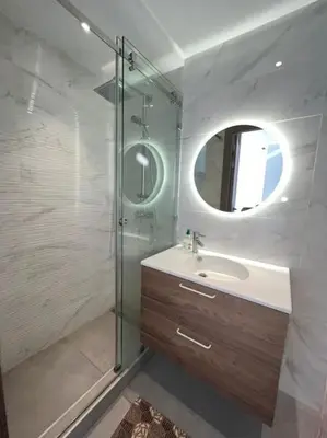 a bathroom with a sink and a shower with a mirror at Appartement vaste et lumineux, Oasis in Casablanca