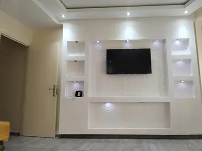 a living room with a tv on a wall with shelves at Sense housse in Rabat