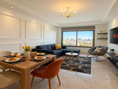 a living room with a table and a blue couch at Cosy sunny central - 2 BDR near train and tram in Casablanca