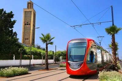 a red tram on a street with palm trees at Cosy sunny central - 2 BDR near train and tram in Casablanca