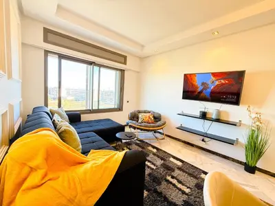 a living room with a blue couch and a tv at Cosy sunny central - 2 BDR near train and tram in Casablanca