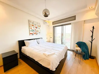 a bedroom with a bed and a large window at Cosy sunny central - 2 BDR near train and tram in Casablanca