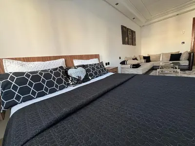 a bedroom with a large bed and a living room at Golden studio in Rabat
