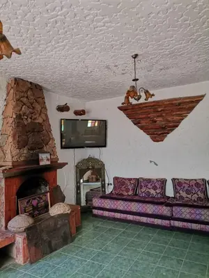 a living room with a couch and a stone fireplace at Auberge les Roches in Al Haouamed