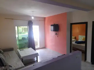 a living room with a bed and a tv on the wall at Auberge les Roches in Al Haouamed