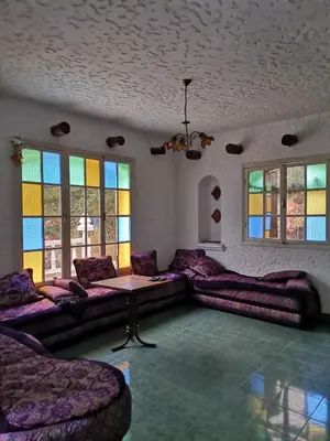 a living room with purple furniture and stained glass windows at Auberge les Roches in Al Haouamed