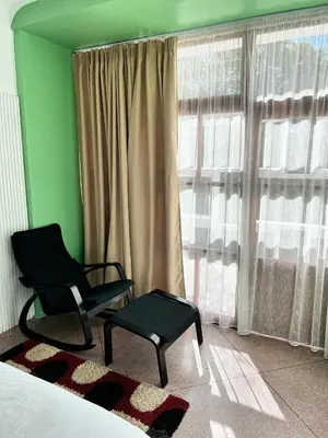 a room with a bed and a chair and a window at Cosy vintage appartement with terrace in Rabat