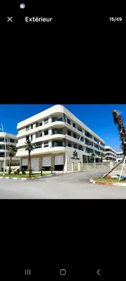 a large white building with palm trees in front of it at appartement haut standing avec piscine a cote de la plage et du golf a bouznika in Bouznika