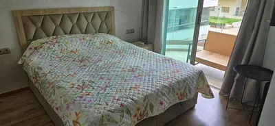 a bedroom with a bed with a flowered comforter and a balcony at appartement haut standing avec piscine a cote de la plage et du golf a bouznika in Bouznika