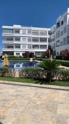 a large apartment building with a pool in front of it at Salah in Bouznika