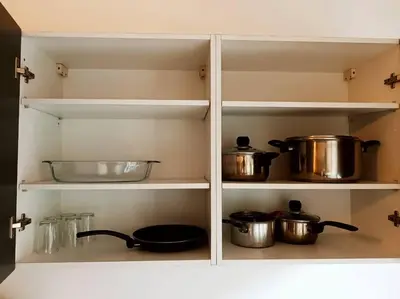 a kitchen cabinet with pots and pans on shelves at Elegant 2-Bedroom Apartment in Vibrant Maarif in Casablanca