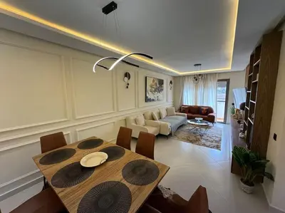 a dining room with a table and a living room at Luxueux Appartement avec Piscine et Terrasse in Bouznika