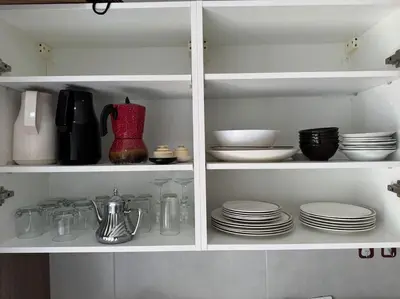 a white cabinet with plates and bowls and utensils at Luxueux Appartement avec Piscine et Terrasse in Bouznika
