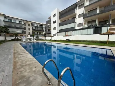 a large swimming pool in front of a building at Luxueux Appartement avec Piscine et Terrasse in Bouznika