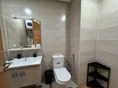 a bathroom with a white toilet and a sink at Luxueux Appartement avec Piscine et Terrasse in Bouznika