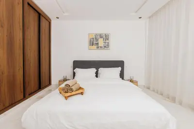 a white bedroom with a large bed with white sheets at Perla in Rabat