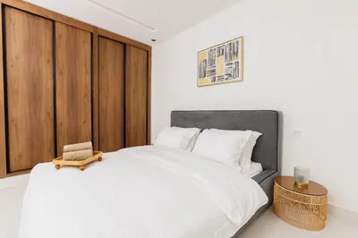 a bedroom with a large white bed with a wooden headboard at Perla in Rabat