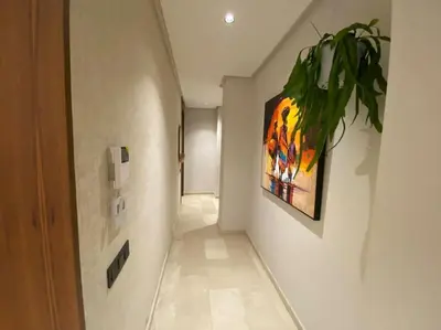 a hallway with a painting and a plant on the wall at Findy Maarif avec jardin privé in Maarif