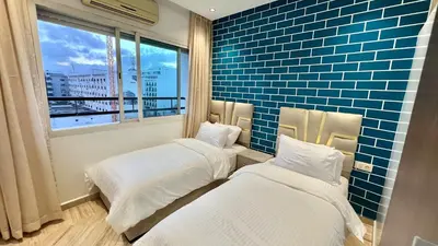 two beds in a room with a blue brick wall at Stylish 2BR Appartement Central - 5 min Casa port in Casablanca