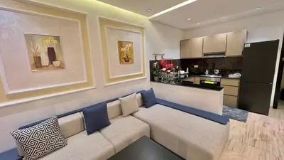 a living room with a couch and a kitchen at Stylish 2BR Appartement Central - 5 min Casa port in Casablanca