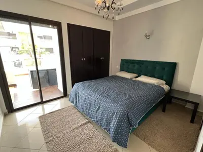 a bedroom with a bed with a green headboard and a window at Appartement Cosy Vue sur Mer in Dar Bouazza
