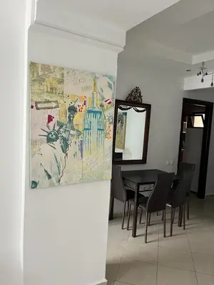a dining room with a table and a painting on the wall at Appartement Cosy Vue sur Mer in Dar Bouazza