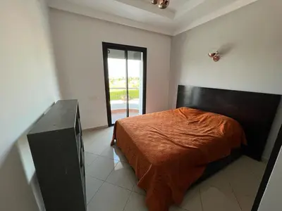 a bedroom with a bed with a orange blanket on it at Appartement Cosy Vue sur Mer in Dar Bouazza