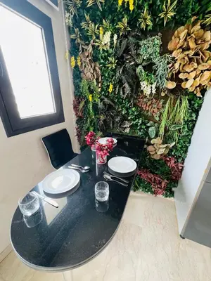 a black table with two plates on it next to a plant wall at STUDIO CASABLANCA BEsT STAY 1 in Casablanca