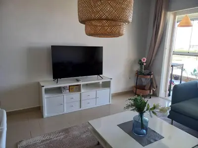 a living room with a flat screen tv on a white cabinet at Appart à Ola Blanca 2 près de Sidi Rahal in Bir Jedíd Saint-Hubert