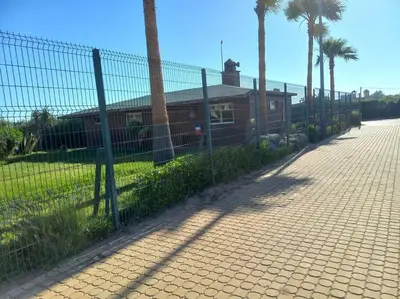 a fence in front of a house with palm trees at Appart à Ola Blanca 2 près de Sidi Rahal in Bir Jedíd Saint-Hubert