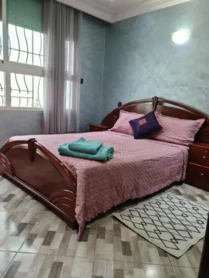 a bedroom with a large wooden bed with pink sheets at Belle maison à Harhoura proche de la plage in Rabat